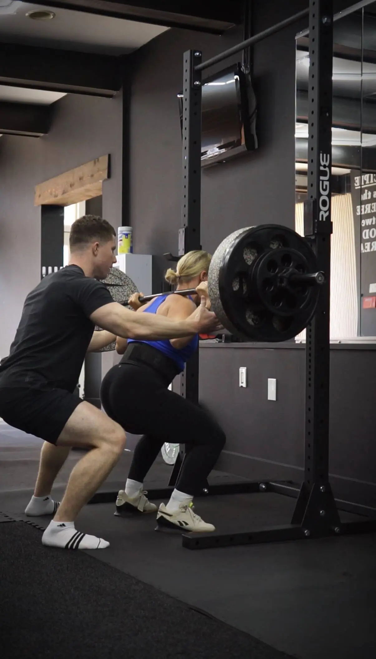 A CKatzFit coach spotting a powerlifting squat