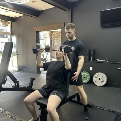 A CKatzFit coach guiding a client through a strength exercise